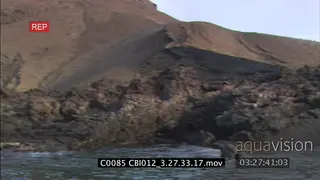 PAN across rocks on beach to island in distance SCENIC