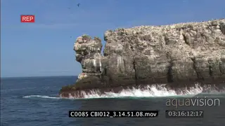 Traveling shot from boat moving past island cliffs protruding into the ocean XLS