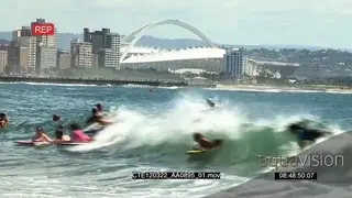 People on surfboards surfing waves Moses Mabhida stadium in BG