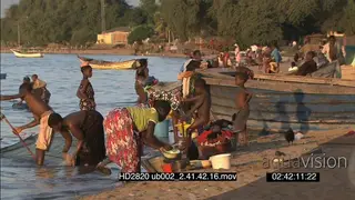 Local woman washing dishes laundry on riverbank young boys pulling fishing nets in BG
