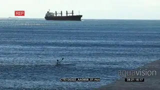 Ship in BG as man paddles across ocean in a canoe