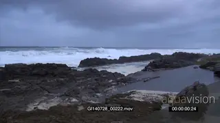 Big waves rolling in over rocks Overcast storm clouds