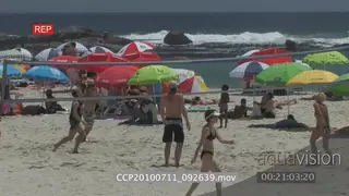 Beachfront landscape shot people under umbrellas others playing games volleyball general.