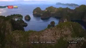 A stunning aerial shot over the sea with green lush islands in the Misool area at sunset