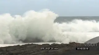 Big waves rolling in over rocks Overcast conditions