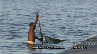 Local woman washing dishes laundry on riverbank pan to young boy pulling fishing nets…